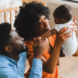 A family holds their newborn baby in their home nursery.